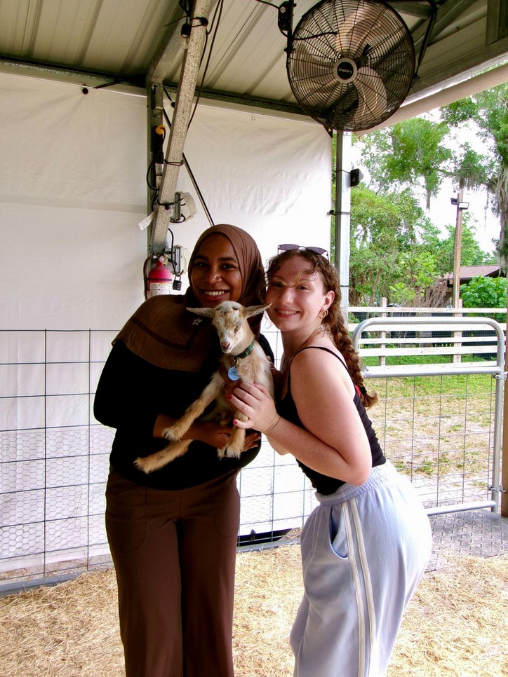 Two Ivys holding a baby goat at the goat yoga gathering